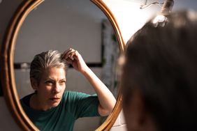Person looking at scalp and checking hair in mirror.
