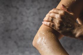 Close-up of person's hand touching their arm in the shower.