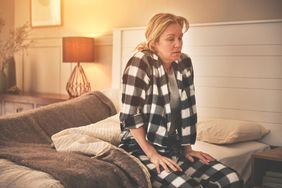 Person looks sick sitting on the edge of their bed.