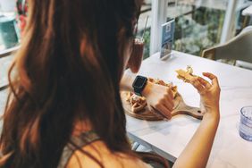 woman checking watch while eating