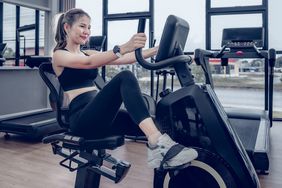 A young woman exercises on a recumbent bike at the gym