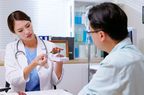 attractive young brunette ponytail female asian doctor wear white coat explaining liver model to male patient at clinic