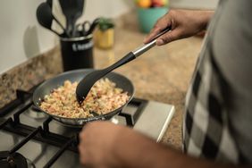 Man cooking scrambled eggs in the kitchen at home