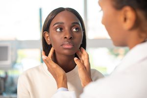 Thyroid health - Endocrinologist examining thyroid gland of female patient 