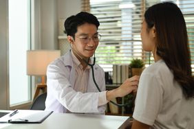 Doctor holding stethoscope examine checking heart lungs of patient in hospital. Medical care, healthcare and people concept.