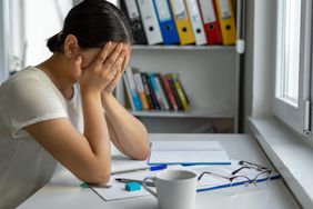 Person at desk with hands on face feeling an impending sense of doom