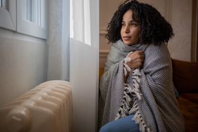 Young woman feel cold in home, wrapped in a blanket.