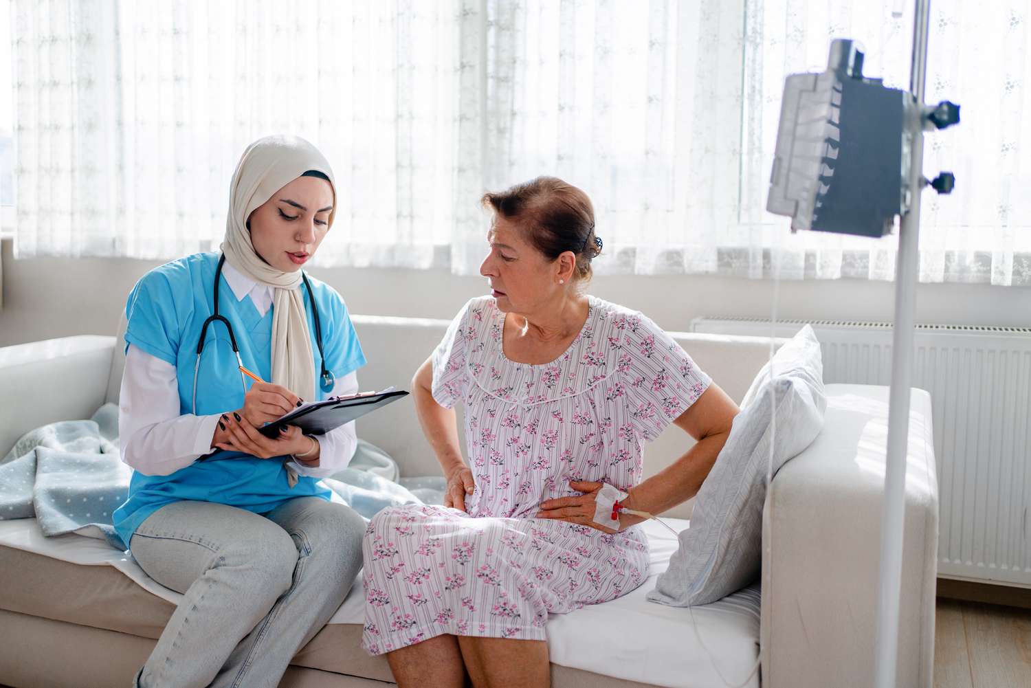 doctor discussing treatment options with person holding their abdomen in pain while sitting on a couch