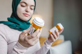 Person holds two pill bottles at home.