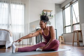 A woman stretching in her home.