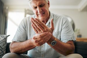An older man massages his hand that is in pain