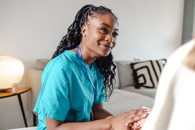 Gynecologist smiling up and comforting at a patient.