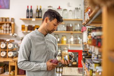 Mixed race male costumer in his 40's checking the organic goods in a small store.