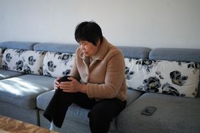Person with joint pain sits on couch and holds their knee in pain.