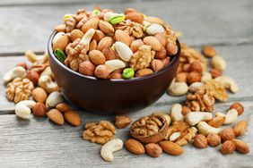 Bowl of mixed nuts on a wooden gray table. Walnut, pistachios, almonds, hazelnuts and cashews, walnut.