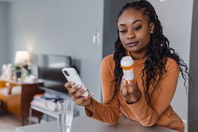A young woman looks at a prescription bottle