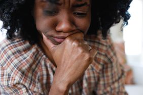 Close-up of distraught woman resting her chin on hand