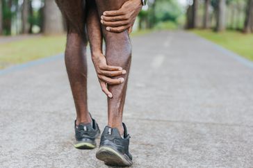 A person gets a muscle cramp in their calf while running