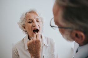 A healthcare provider looks into an older woman's mouth