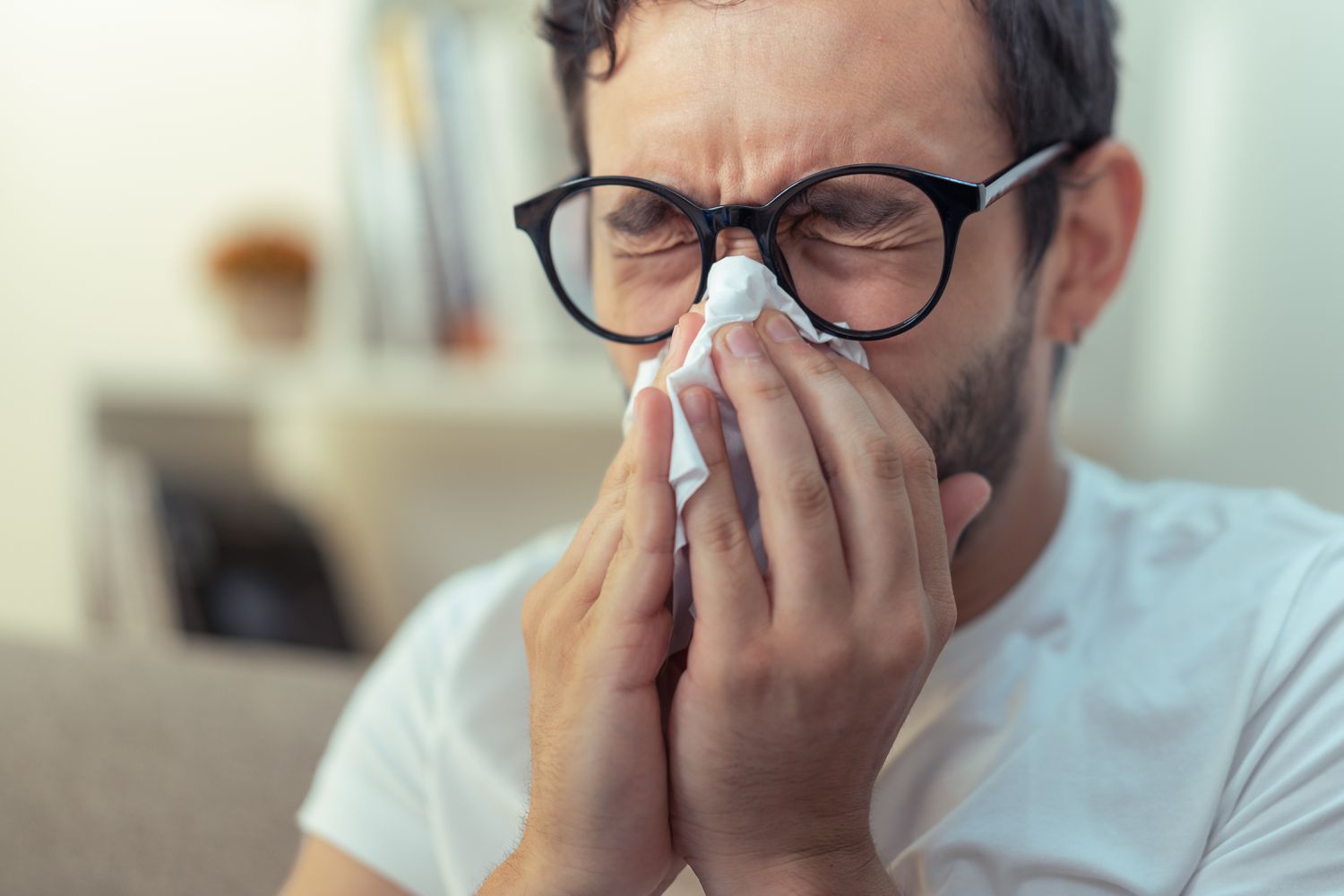 A man blows his nose into a tissue