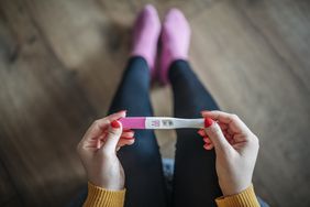 Person holds a positive pregnancy test.