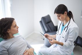 Doctor talking to patient about stomach symptoms