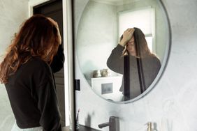 Person looks stressed in their bathroom mirror. 