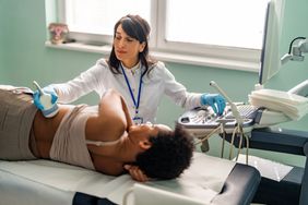 doctor performing an ultrasound on person laying on an exam table to check for kidney disease in the back