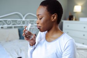 Person drinks a glass of water in their bedroom.