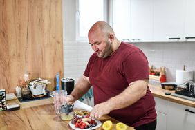 person in kitchen preparing a meal full of fruits and vegetables as part of their weight management plan