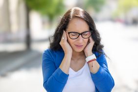 A woman covers her ears in pain