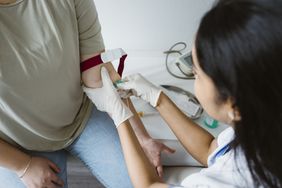 A healthcare provider draws blood from a person's arm