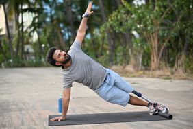 A man with a prosthetic leg practicing a side plank exercise in an outdoor setting