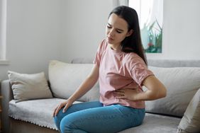 Person with left upper quadrant abdominal pain sitting on couch