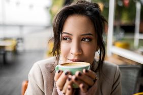 Woman drinking a cup of coffee outside at a cafe