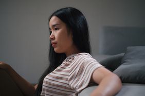 Person sits on floor by couch and looks a little depressed.