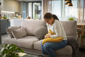 person with right upper quadrant pain experiencing discomfort while sitting on couch