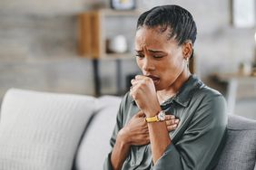 Person coughing while sitting on the couch.