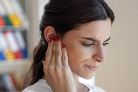 Person holds their hand to their ear, apparently in pain.