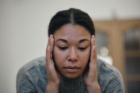 Close up of person with a headache, with their hands on their temples.