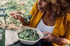 Person eats a spinach salad outside.