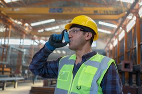 A man working in a factory uses an inhaler