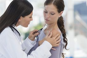 Dermatologist examining patient's shoulder for keratosis pilaris