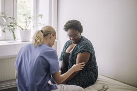 A healthcare provider looks at the crease of a woman's arm