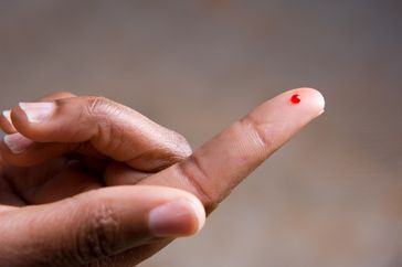 A drop of blood on a fingertip. 