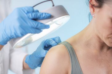 dermatologist looking at woman's skin on her back