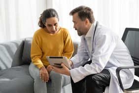 A male doctor shows a female patient information on a tablet