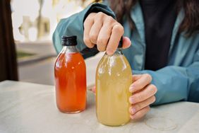 woman screwing the cap off a bottle of kombucha