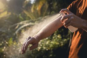 Man applying insect repellent to his arm to help prevent mosquitos from biting him.