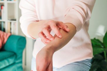 A person itches their forearm